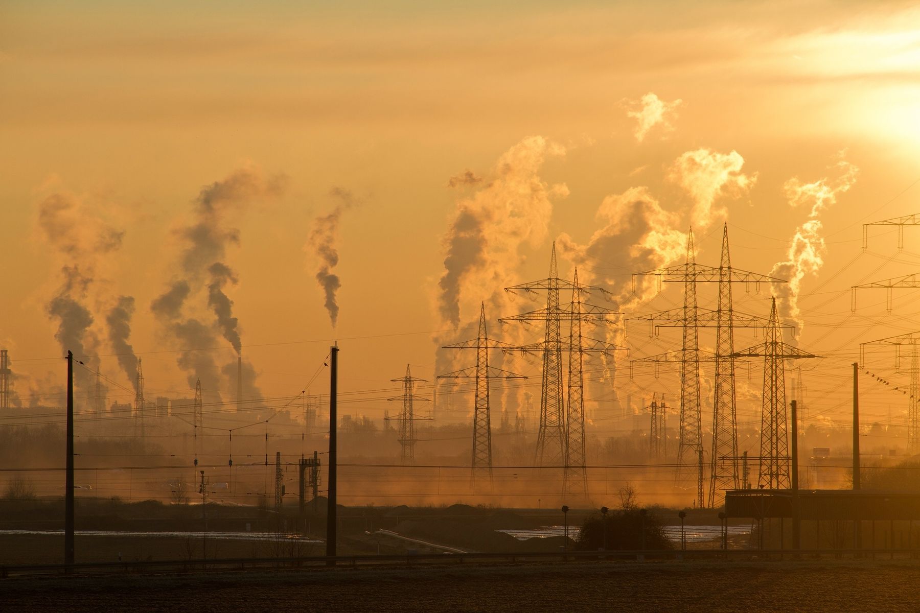 Industrial power corridor at dawn — transmission lines and plant horizon